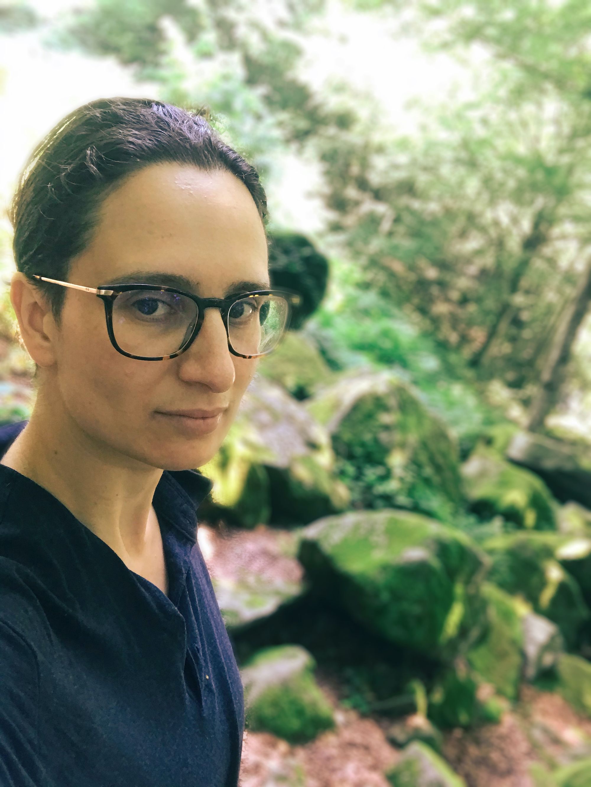 Julia March in the woods with some mossy rocks in the background.